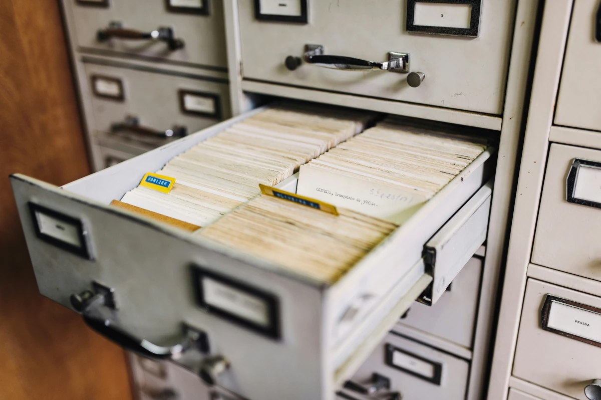 A drawer pulled out from a filing cabinet with paper index cards inside.